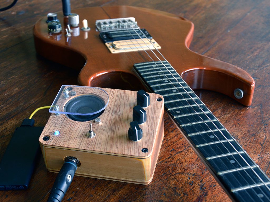 Moon Canoe Brak ver2 portable usb powered practise amp with overdrive switch next to electric guitar